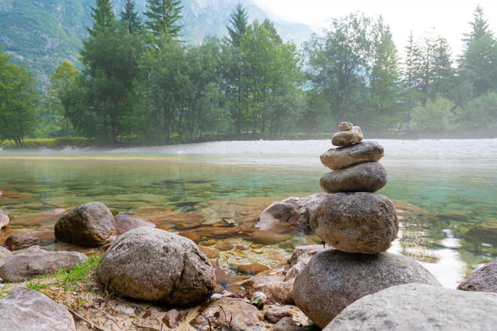 A cairn of smooth river stones balanced at the edge of a clear mountain river