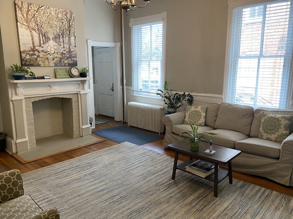 The main waiting area with a fireplace, soft sofa, and plants