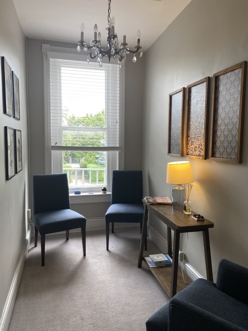 The upstairs waiting area with two blue chairs and a chandelier